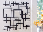 Black geometric wall decor with square outlines and bar-like segments in a grid
