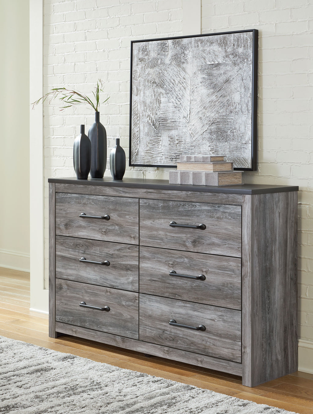 Dark gray dresser with wall mirror and four drawers, metal bar handles visible