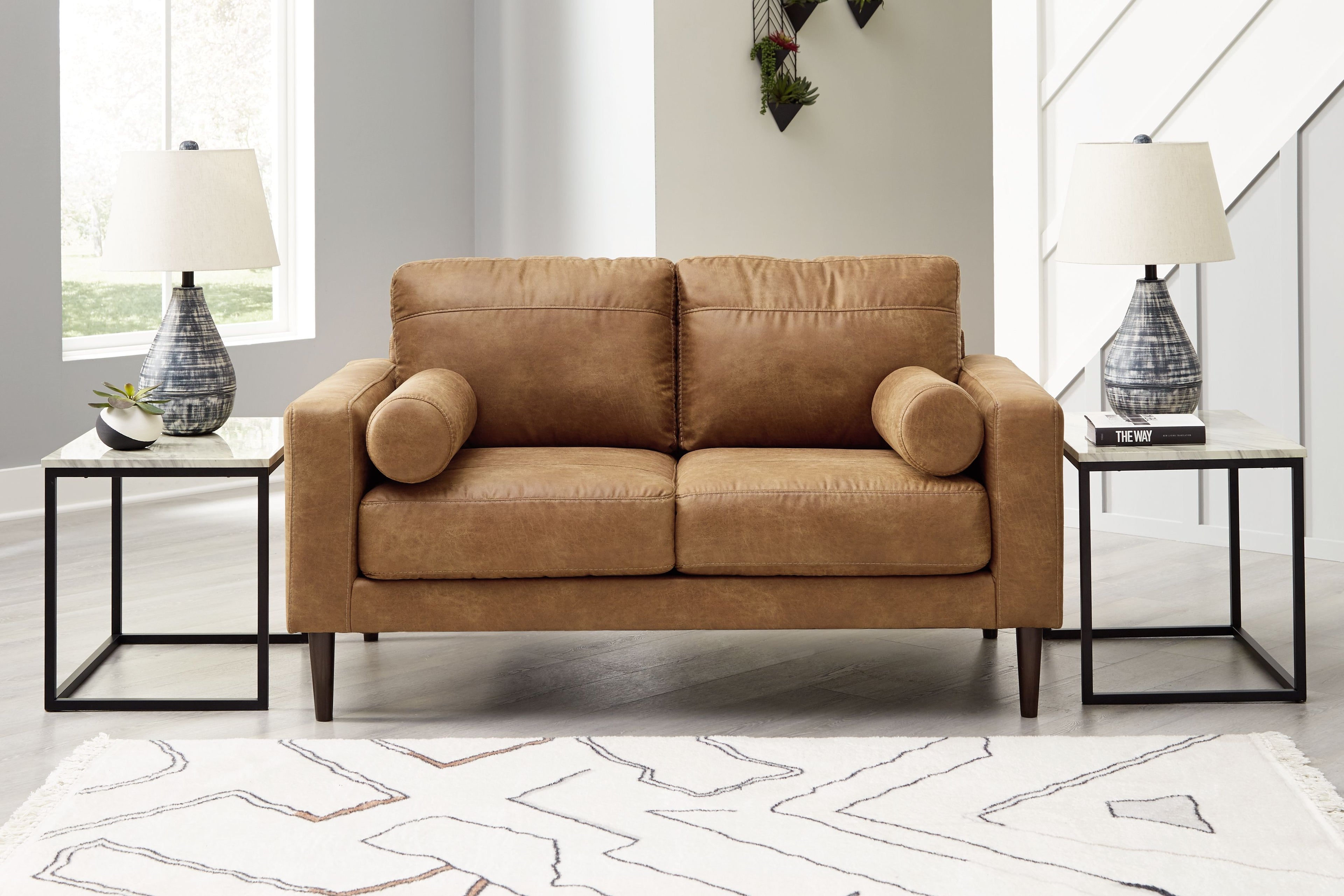 Caramel-brown loveseat with two-seat design and rounded rolled arms, styled in room.