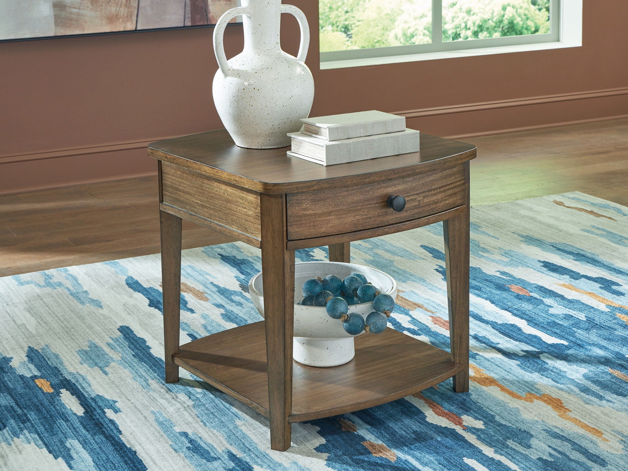 Light brown rectangular wooden end table with drawer knob and lower shelf.