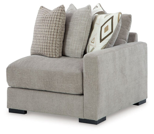 Light gray corner armchair with dark feet and solid plus patterned throw pillows