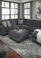 Dark gray sectional sofa with corner chaise and ottoman, white throw blankets