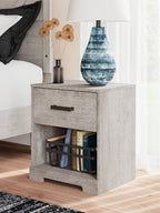 Whitewash one-drawer night stand with black bar pull and open shelf holding books