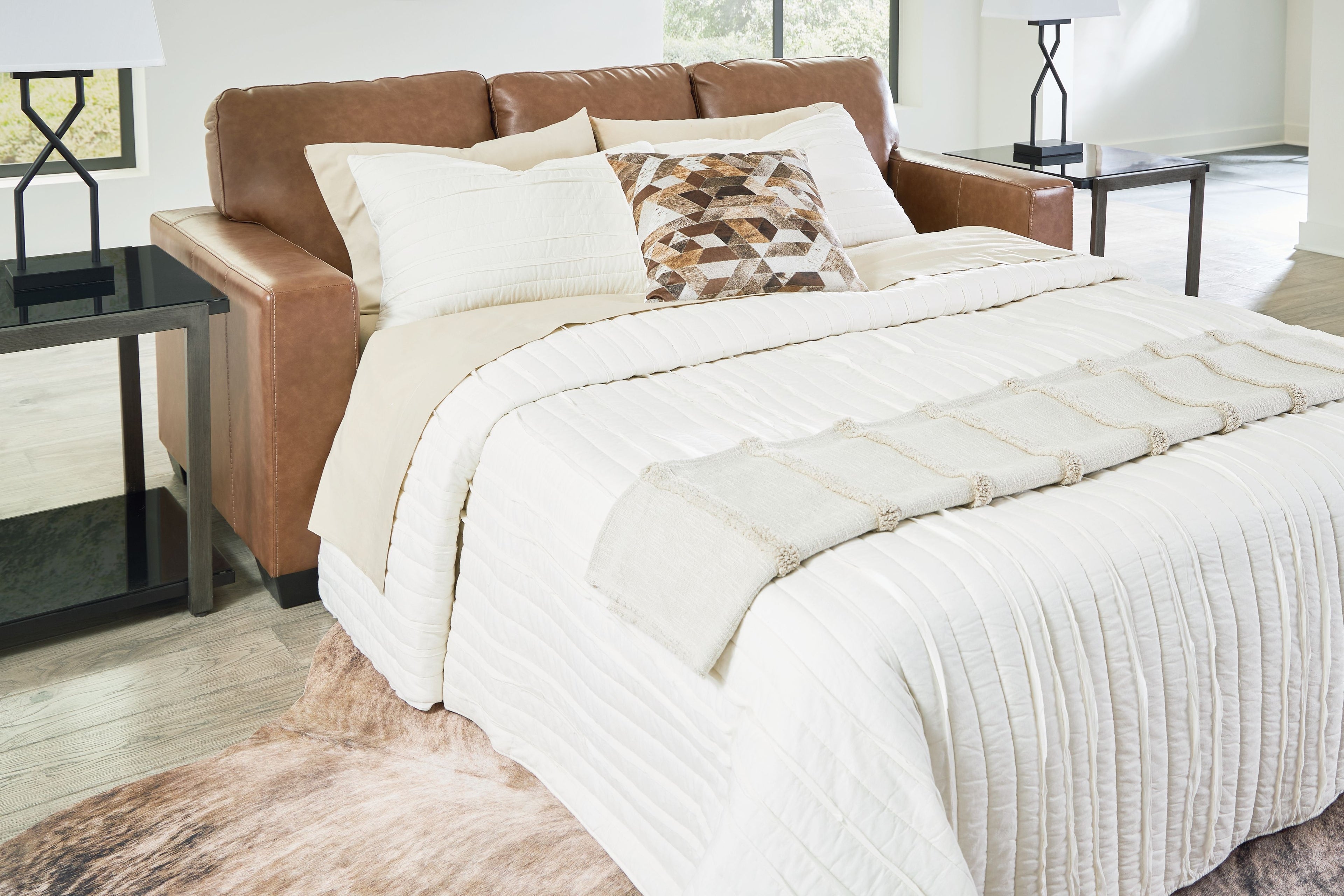 Caramel queen sofa sleeper shown as a bed with white bedding and pillows