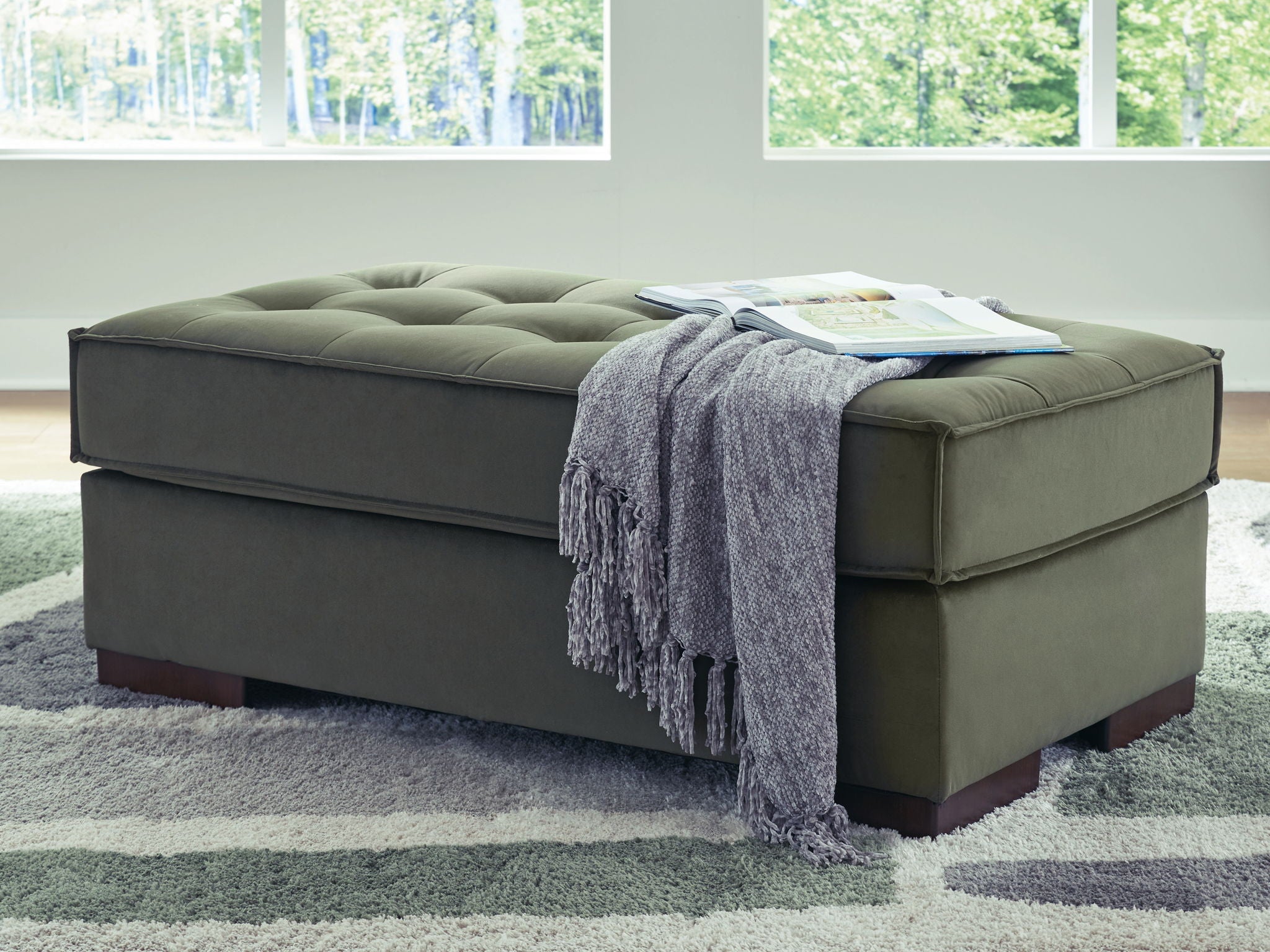 Olive upholstered accent ottoman with tufted top and draped throw blanket