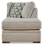 Corner chaise with textured light gray fabric, rounded back, and geometric accent pillows