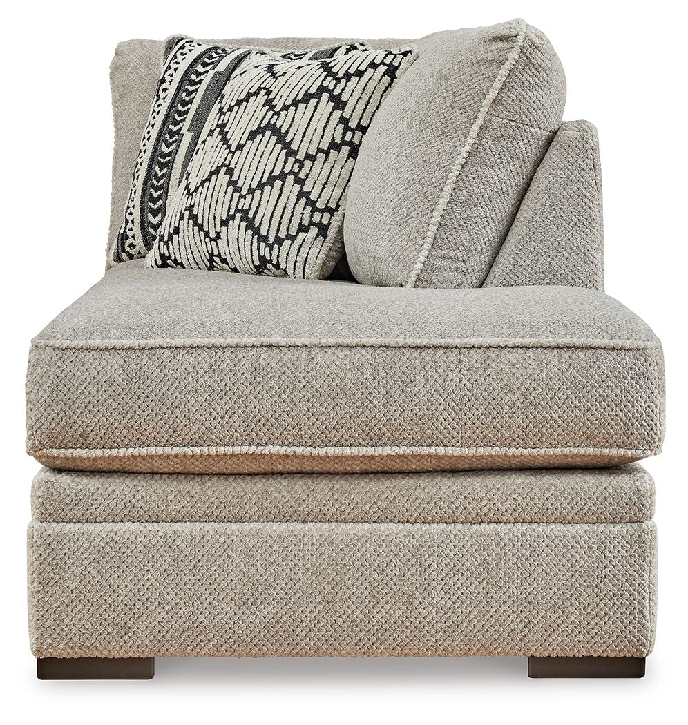 Corner chaise with textured light gray fabric, rounded back, and geometric accent pillows
