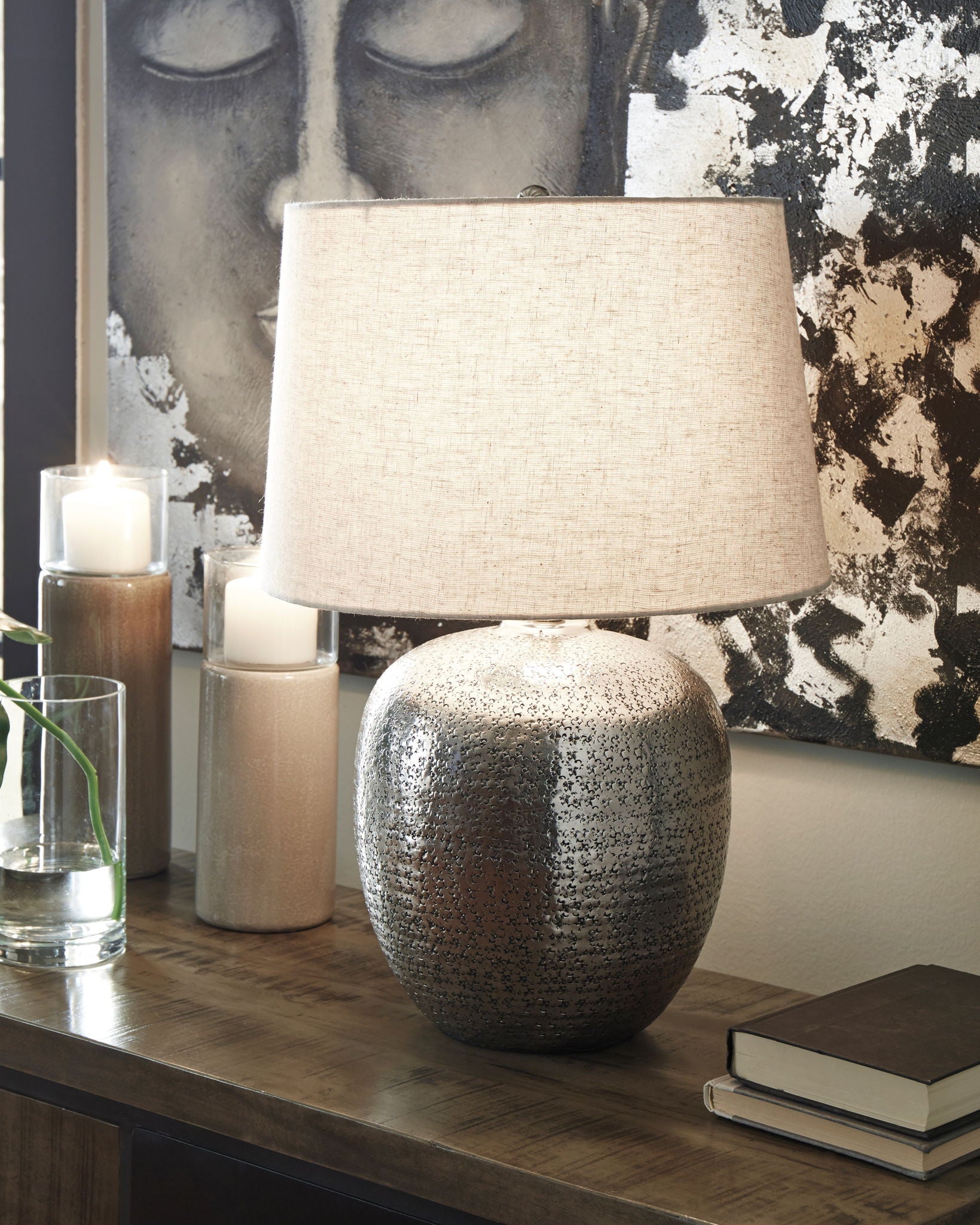 Antique silver metal table lamp with textured base and beige fabric drum shade on table