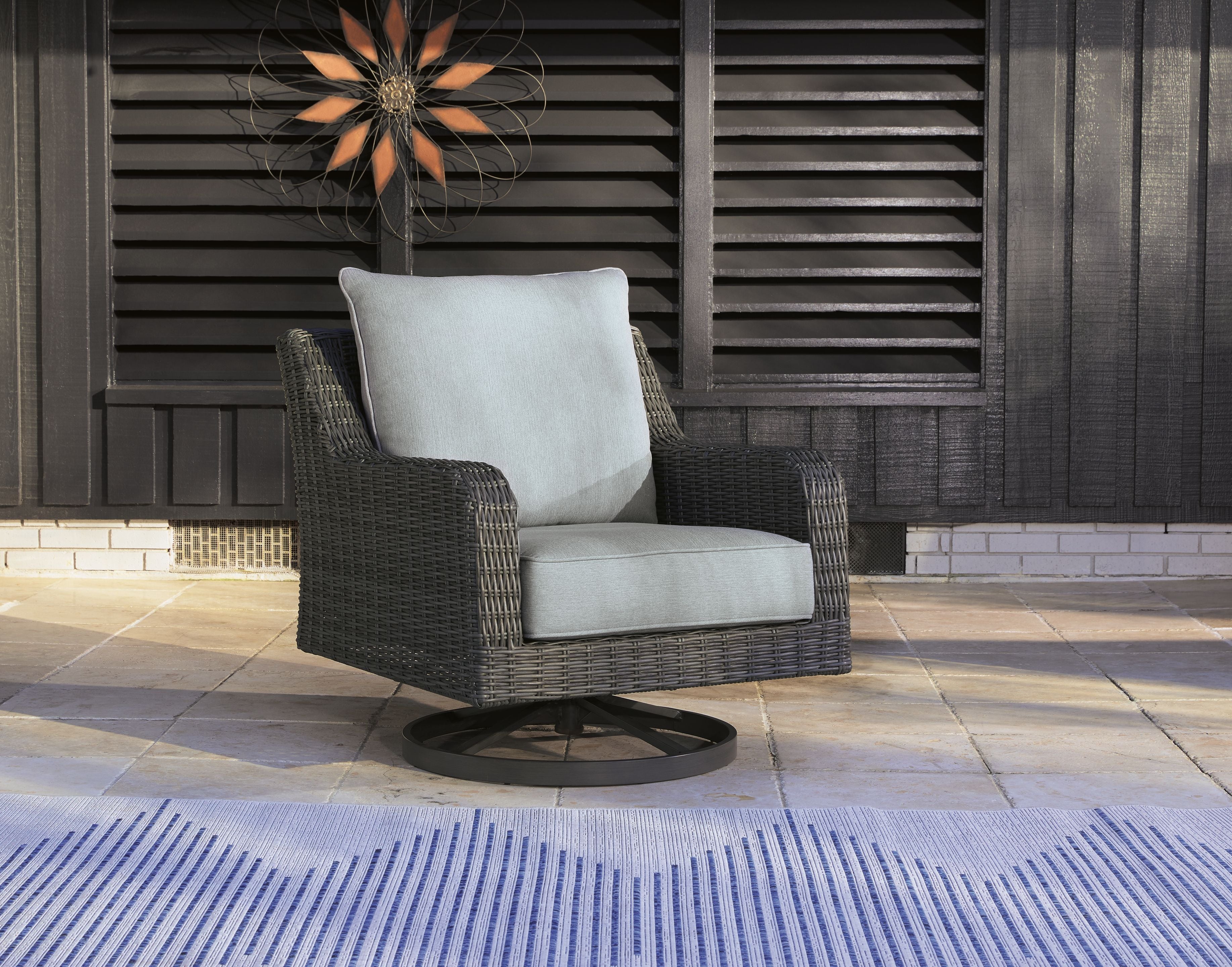 Gray swivel lounge chair with light gray cushion and dark woven wicker frame