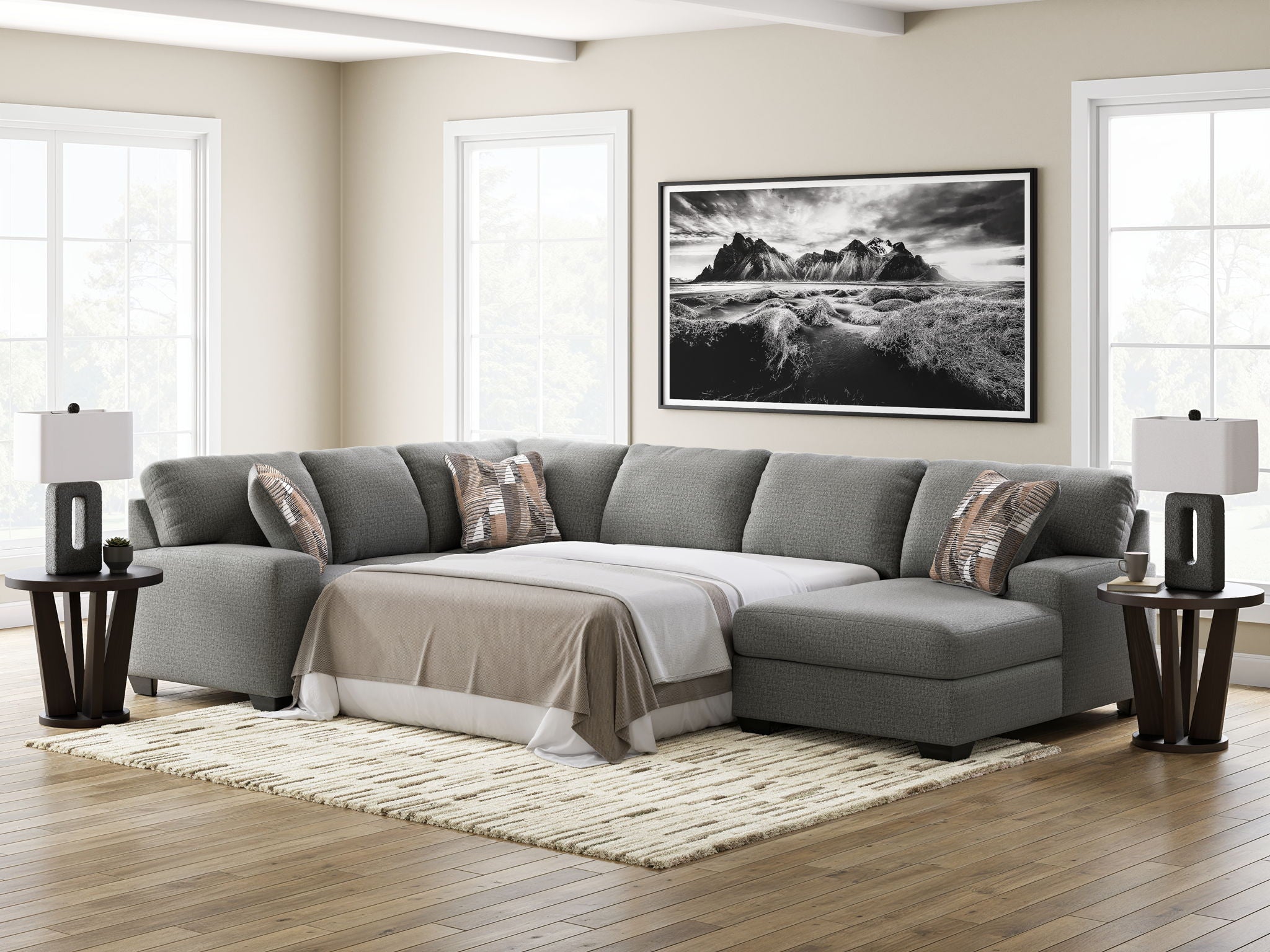 Gray sectional sleeper sofa with chaise, square arms, white bed cover, and accent pillows