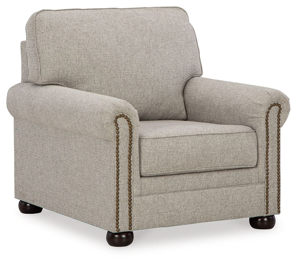 Upholstered armchair in light beige fabric with rolled arms and nailhead trim