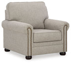 Upholstered armchair in light beige fabric with rolled arms and nailhead trim