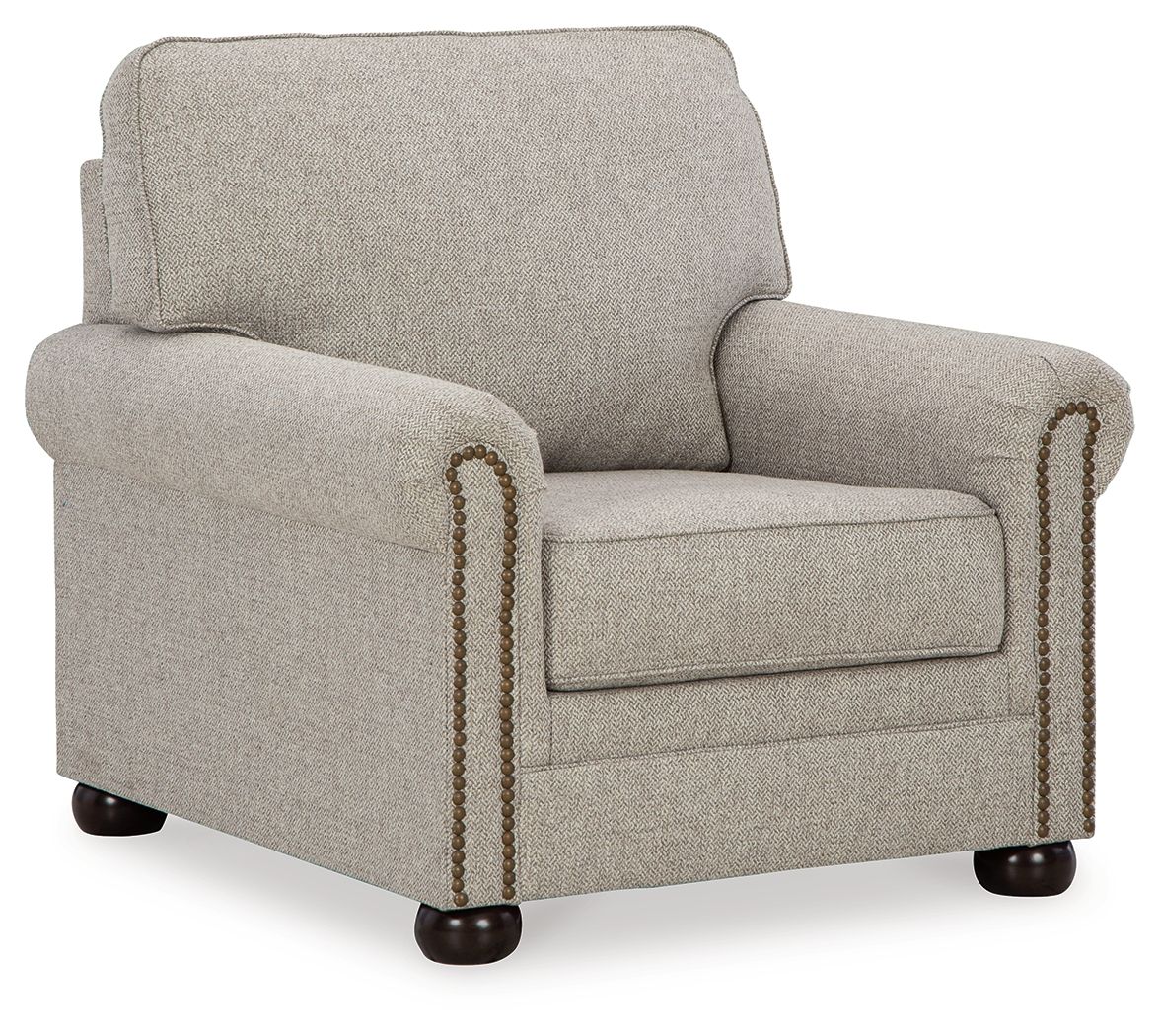 Upholstered armchair in light beige fabric with rolled arms and nailhead trim