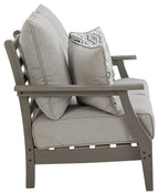 Gray upholstered loveseat with back cushions and a diamond-pattern throw pillow on the arm.