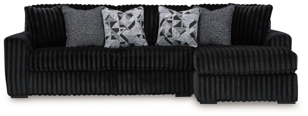 Black corded sectional sofa with gray accent pillows and geometric patterned cushions
