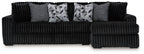 Black corded sectional sofa with gray accent pillows and geometric patterned cushions