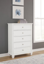 White five-drawer chest with round knobs and crown molding, standing on short legs.
