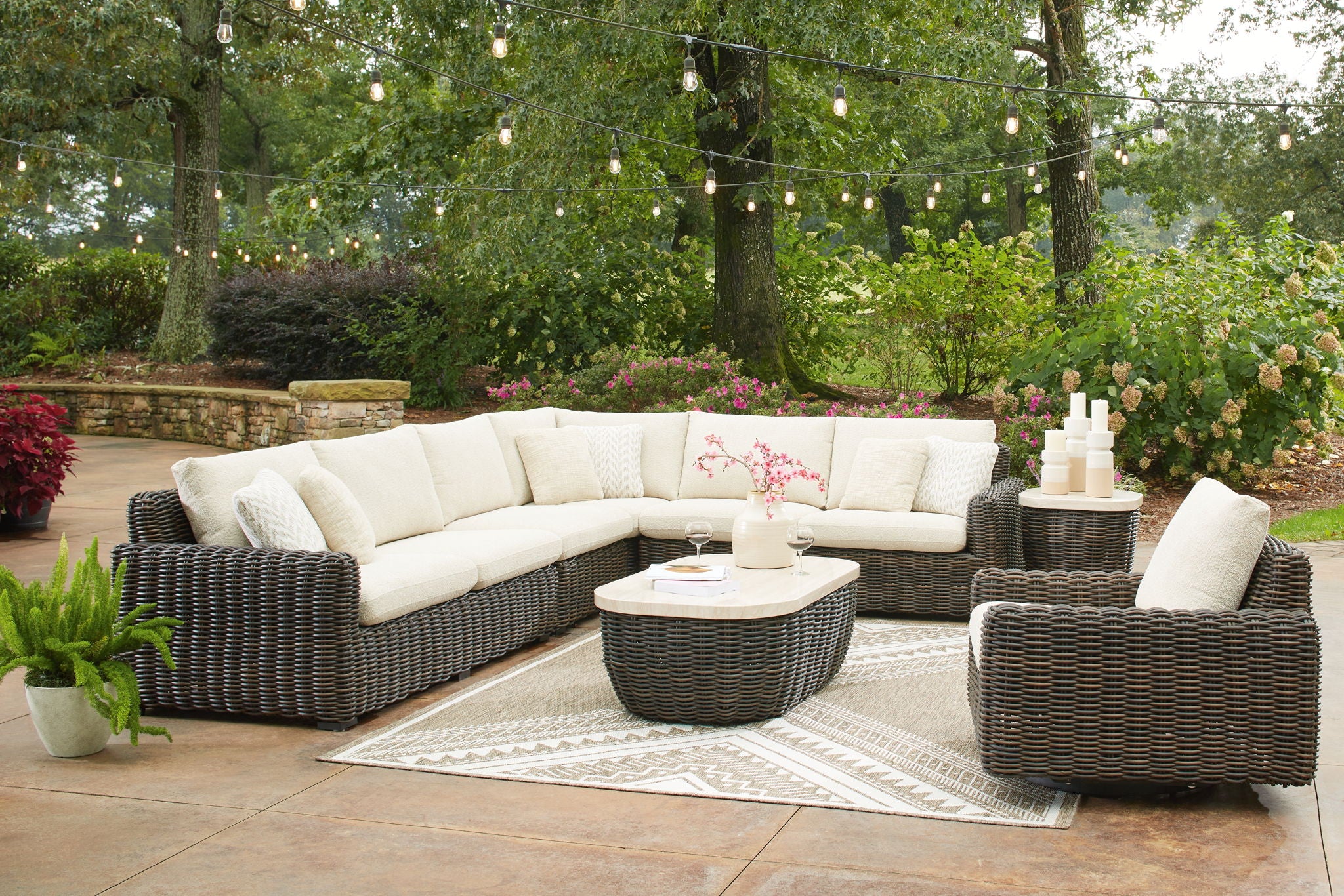 Outdoor seating set with dark brown wicker sectional, round table, and glider chair