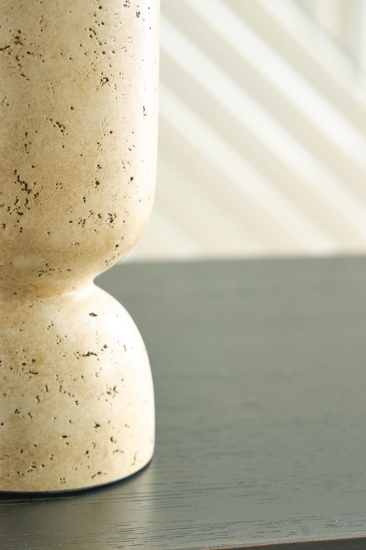 Beige speckled vase bottom on tabletop with rounded pedestal foot
