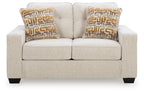 Light beige upholstered loveseat with two square geometric-pattern throw pillows