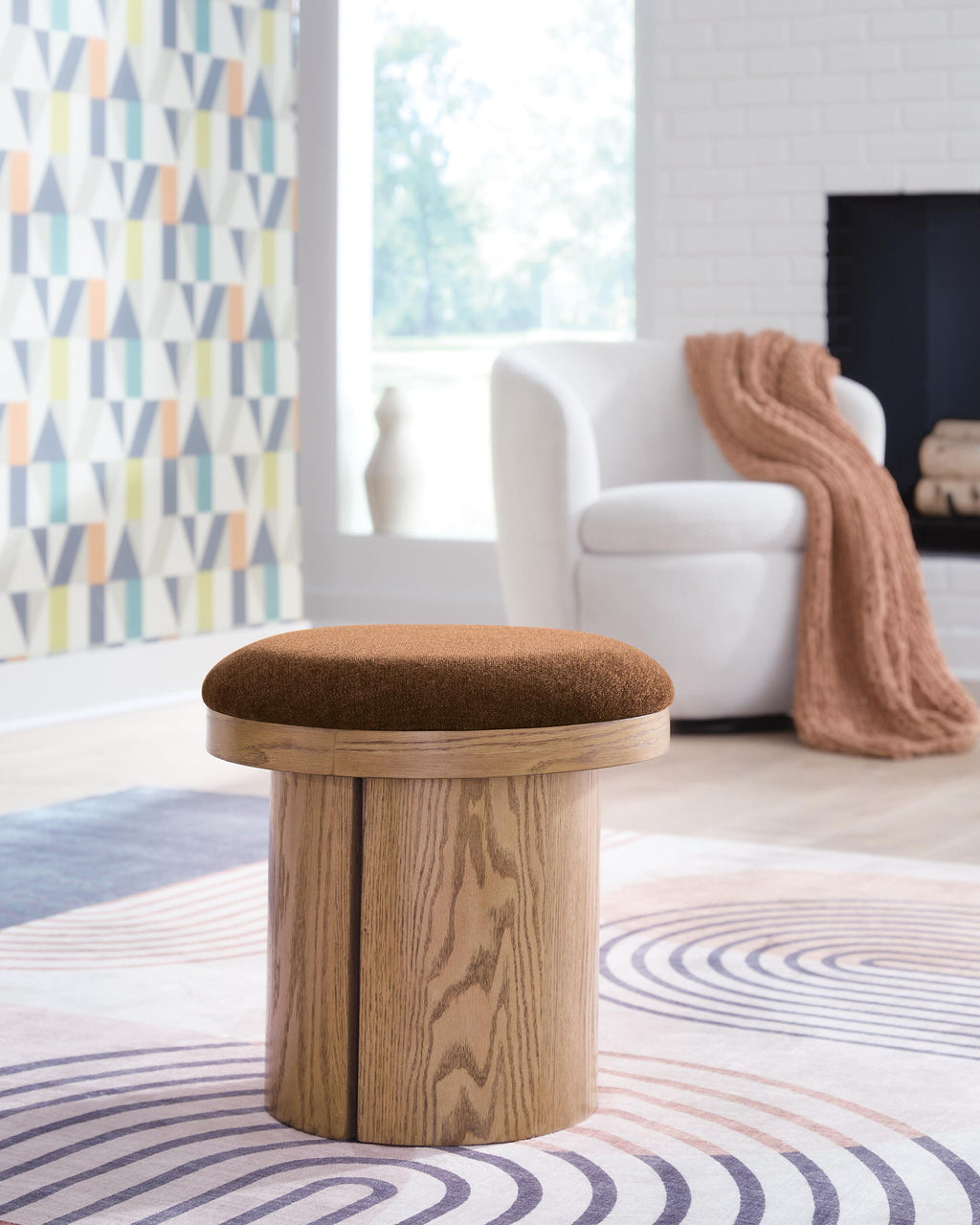 Small round accent ottoman with brown fabric cushion and light wood legs