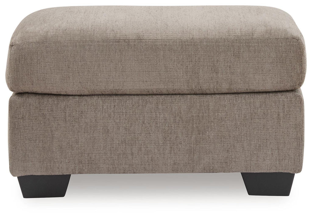 Tan fabric ottoman with thick padded top and dark block legs