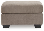 Tan fabric ottoman with thick padded top and dark block legs