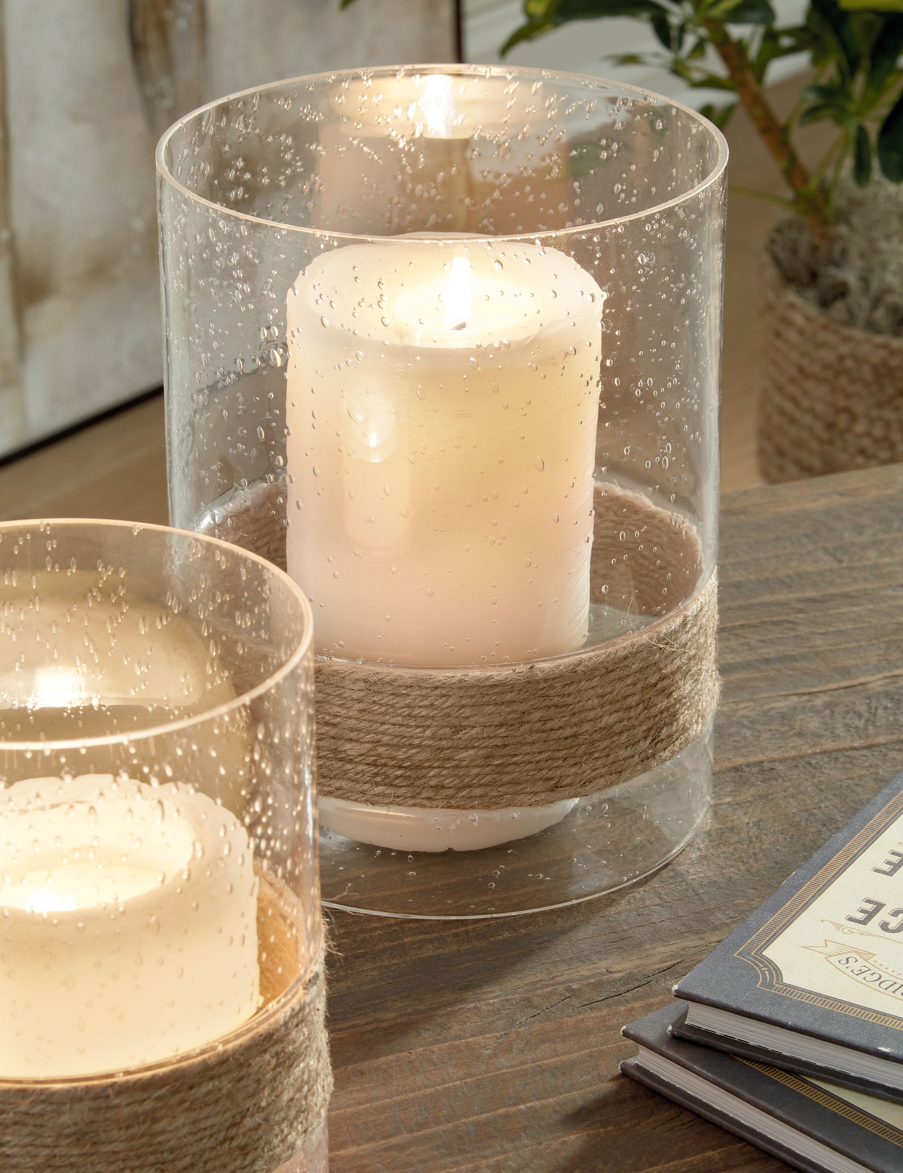 Clear glass candle holders with jute wrap, each holding a lit pillar candle