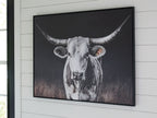 Framed wall art showing a white cow portrait with long horns on dark background