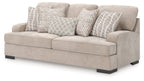 Taupe upholstered sofa with four decorative pillows, including striped and checkered covers