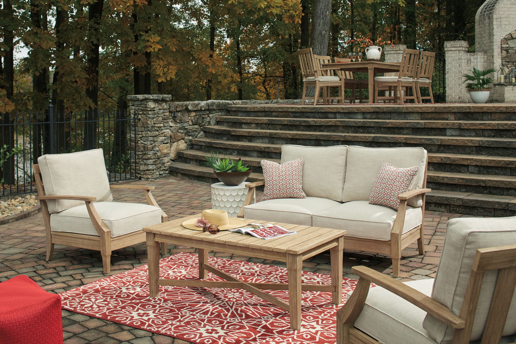 Beige outdoor lounge set with loveseat, two chairs, and patterned accent pillows