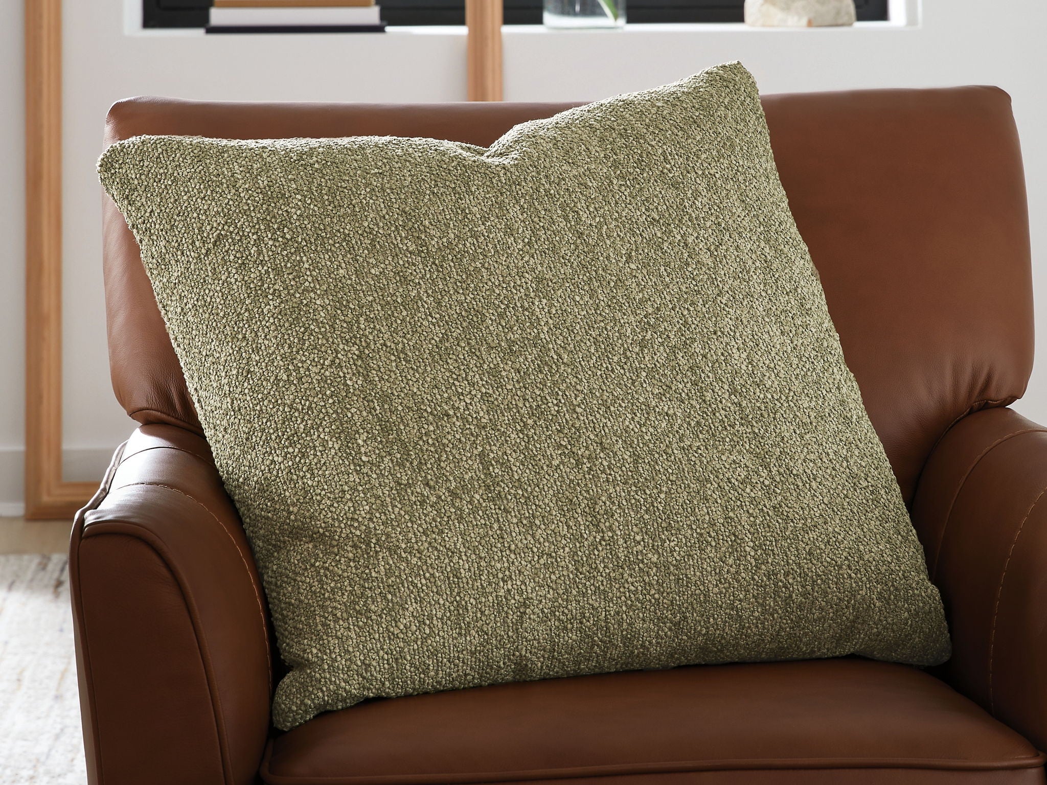 Green square throw pillow on brown leather armchair