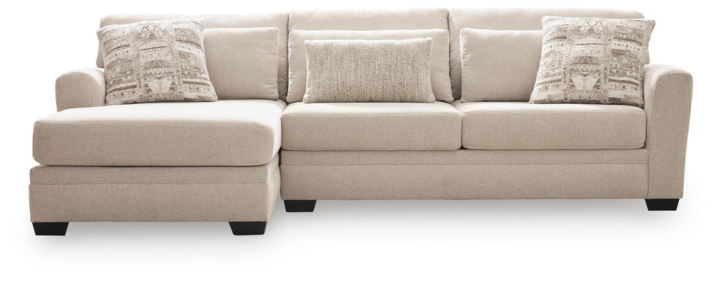 Light beige sectional sofa with chaise, clean-lined arms and two patterned accent pillows