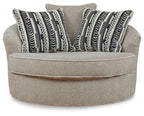 Light beige oversized accent chair with striped geometric throw pillows and round swivel seat