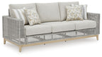 Gray woven outdoor loveseat with seat cushions and two patterned throw pillows