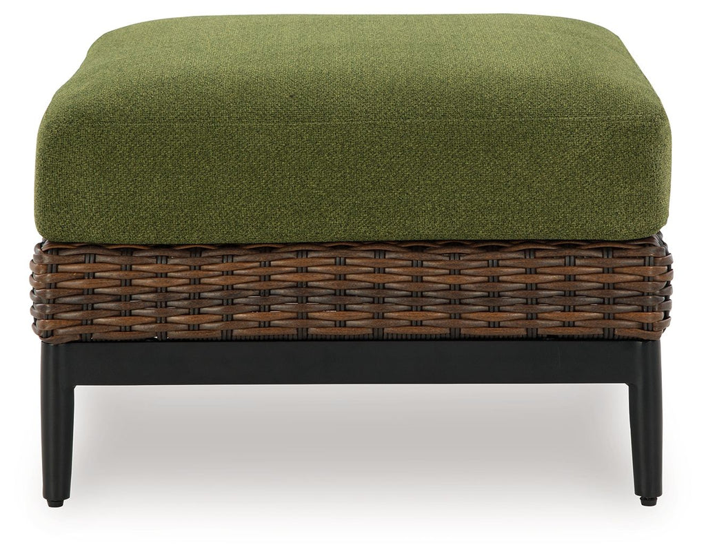 Brown wicker ottoman with green cushion and dark legs