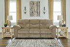 Reclining sofa in beige fabric with three seat sections and rolled armrests, styled in a room.