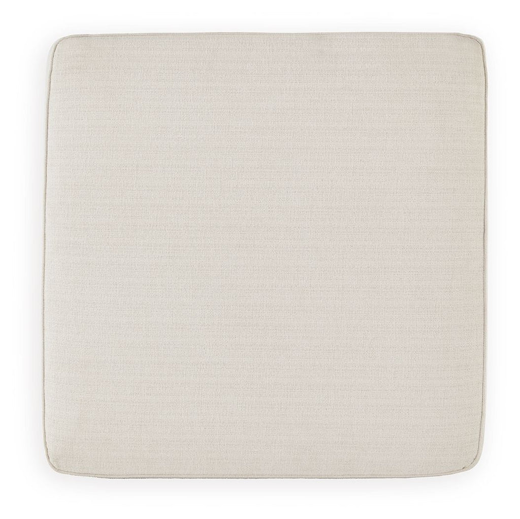 Square ottoman seat upholstered in beige fabric with rounded corners.