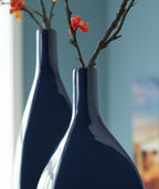 Close-up of glossy blue ceramic vase with stems and small blossoms