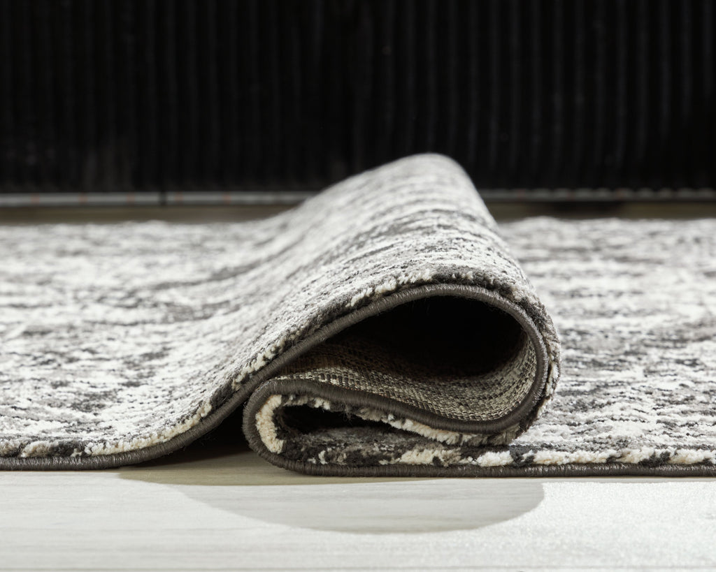 Glennisman rug corner close-up, short pile with gray top and dark underside, folded edge