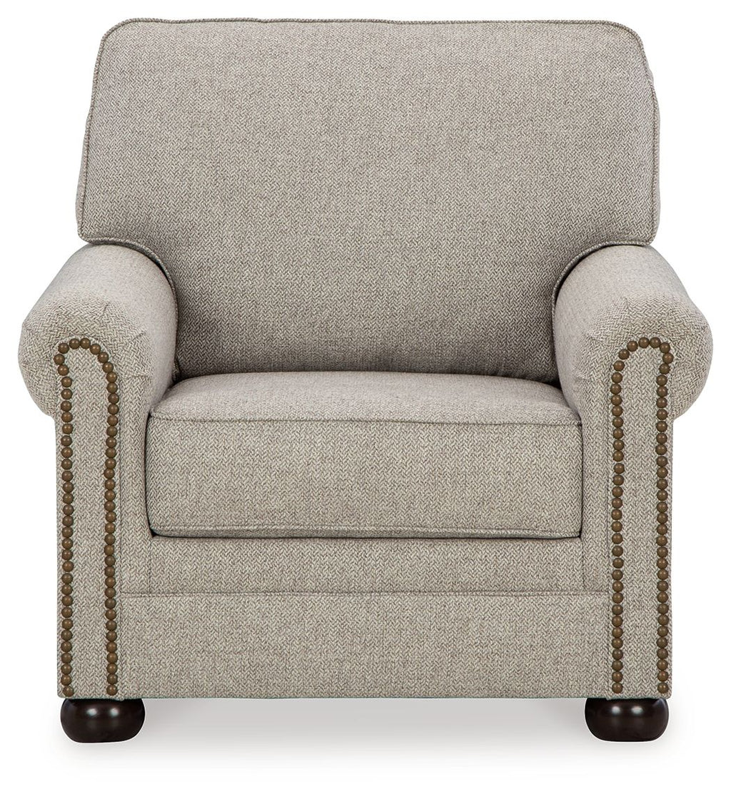 Light beige upholstered armchair with rounded arms and beaded nailhead trim