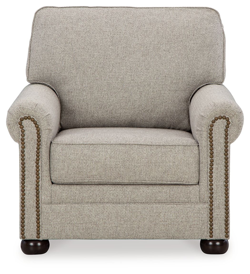 Light beige upholstered armchair with rounded arms and beaded nailhead trim