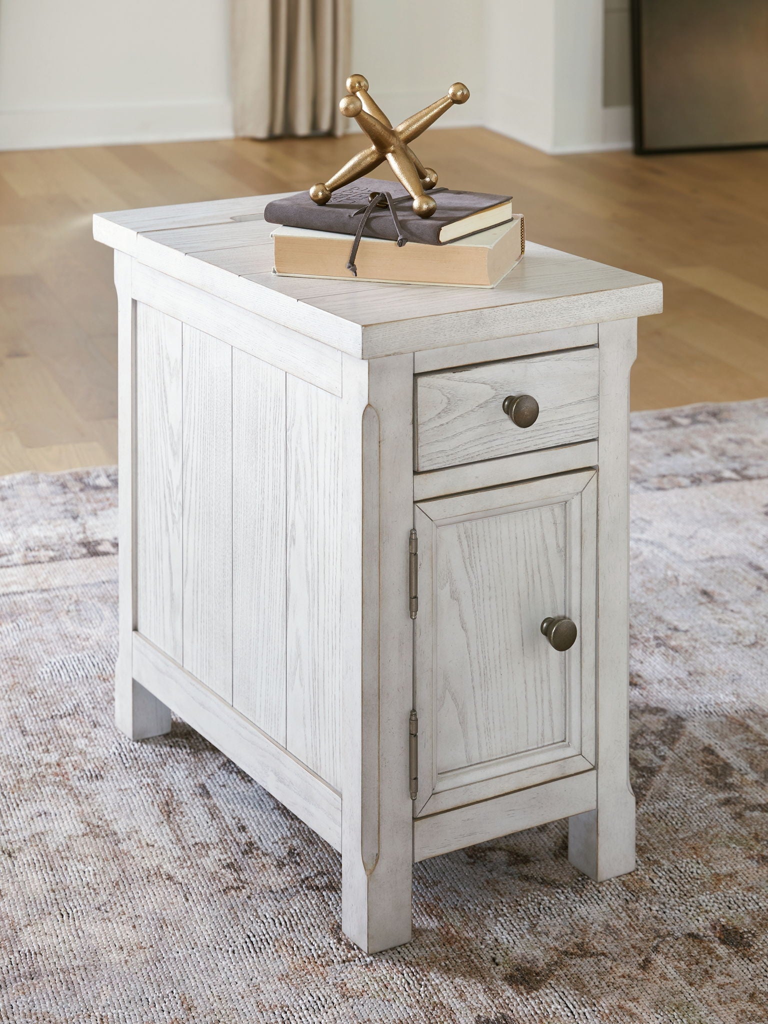 White side table with paneled cabinet doors and a drawer, distressed wood finish.