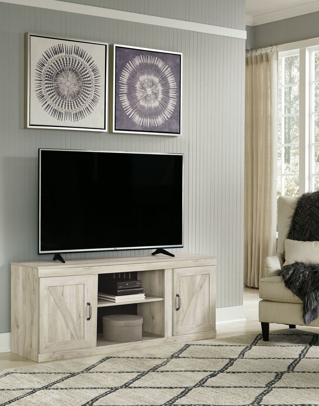Light beige wood TV console with two doors and center shelf, holding TV and media