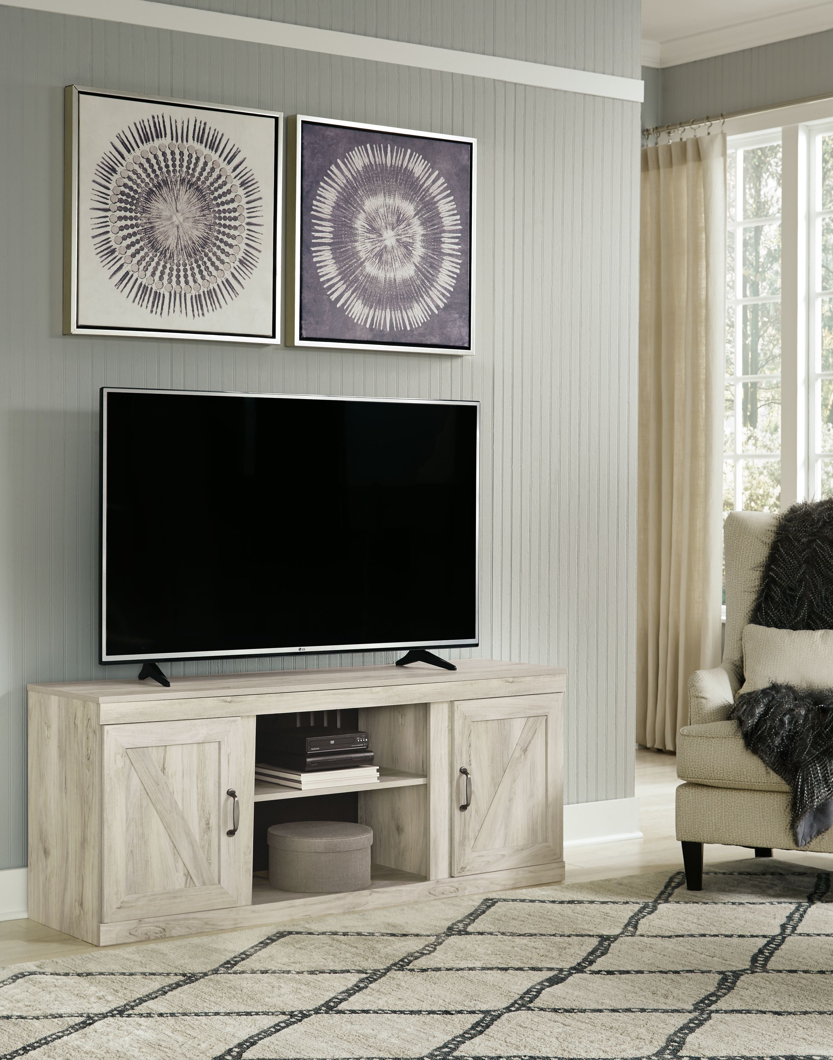 Light beige wood TV console with two doors and center shelf, holding TV and media
