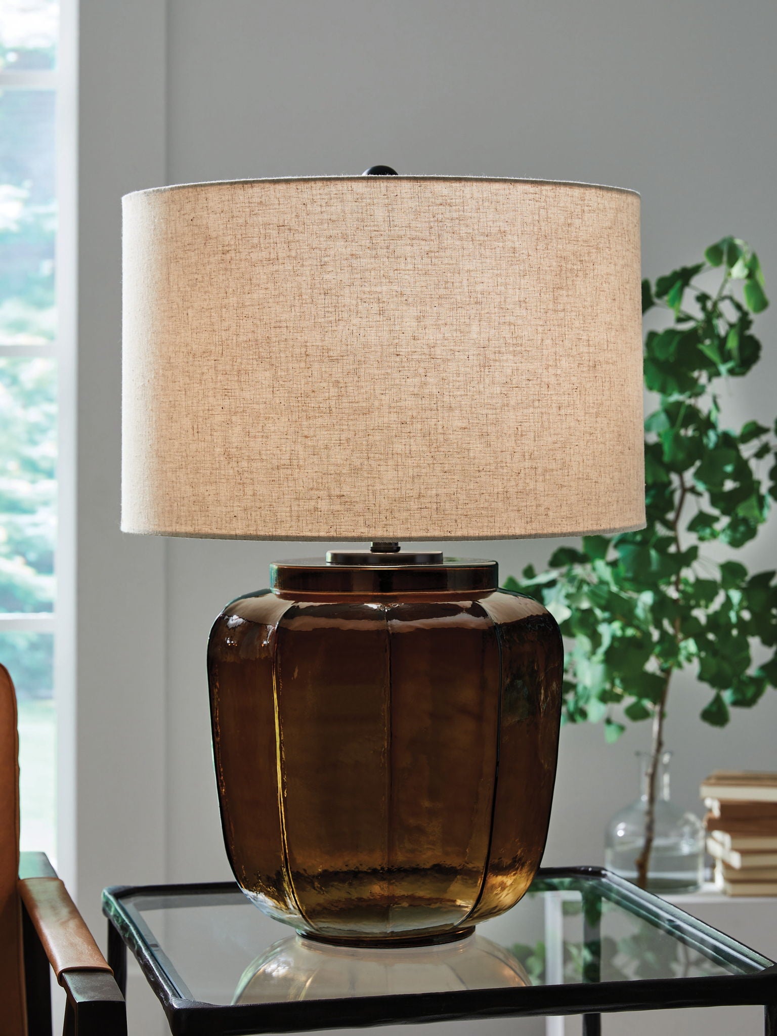 Amber glass table lamp with beige drum shade and faceted rounded body
