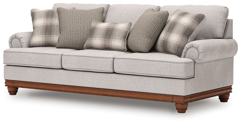 Light gray sofa with plaid and solid pillows, wide seat, tufted arms, wooden legs
