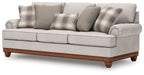 Light gray sofa with plaid and solid pillows, wide seat, tufted arms, wooden legs