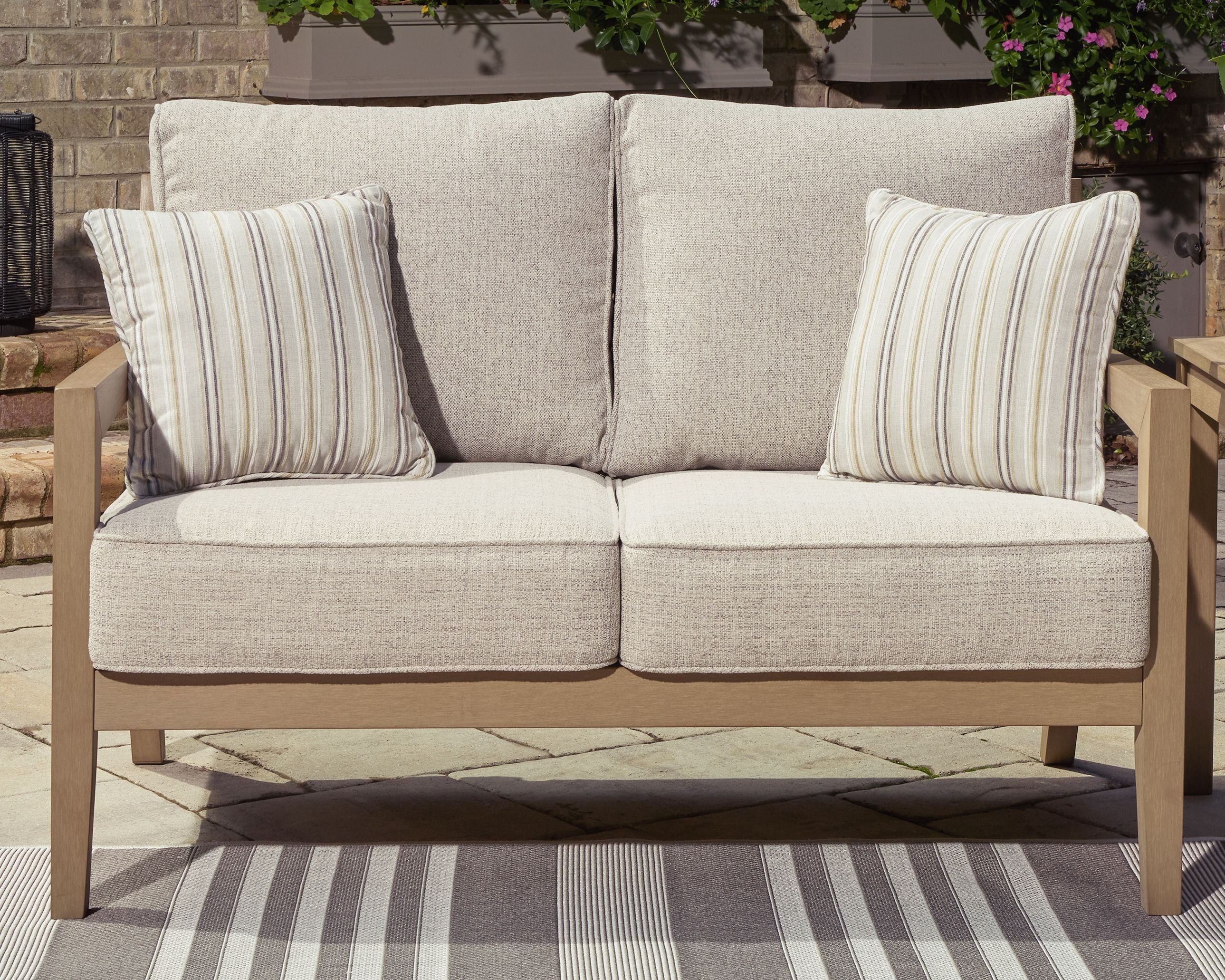 Beige loveseat with two striped throw pillows and two back cushions, driftwood frame