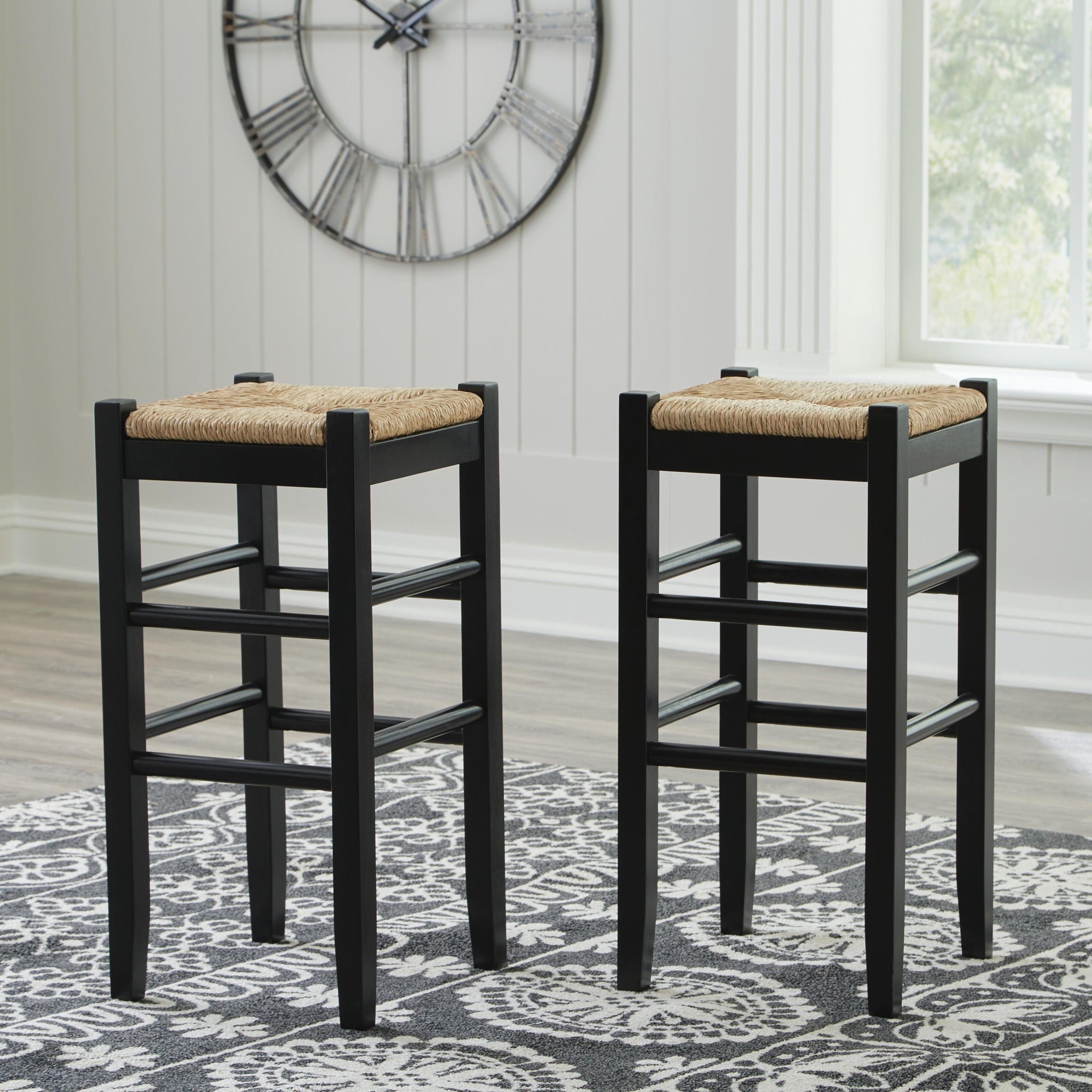 Two tall black stools with woven beige seat pads and slatted side bars